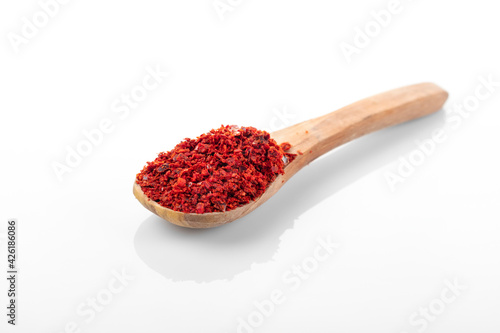 Chili pepper flakes. Chili pepper flakes in wooden spoon, on white background.