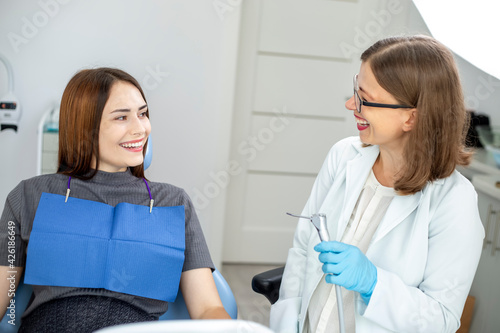 A woman patient sits in a dental chair at a dentist doctor's appointment. A girl with a beautiful smile and white even teeth.