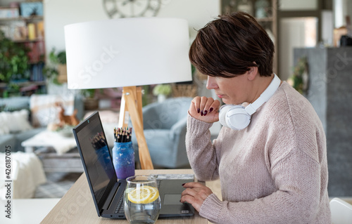 Homeoffice, praca zdalna podczas pandemi koronawirusa, kwarantanna domowa, kobieta pracuje zdalnie przez internet w domowym biurze photo