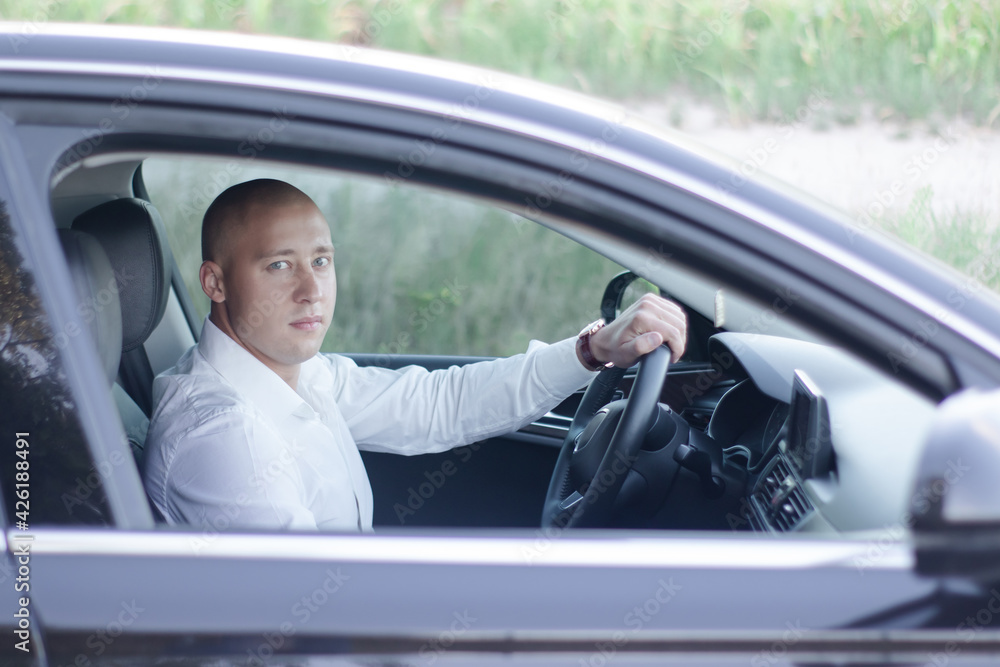 handsome bald man in a suit in a luxury car. businessman in automobile