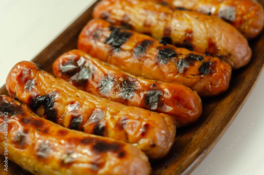 Grilled classic British sausage made from prime cuts of pork on the wooden plate Grilled classic British sausage made from prime cuts of pork on the wooden plate