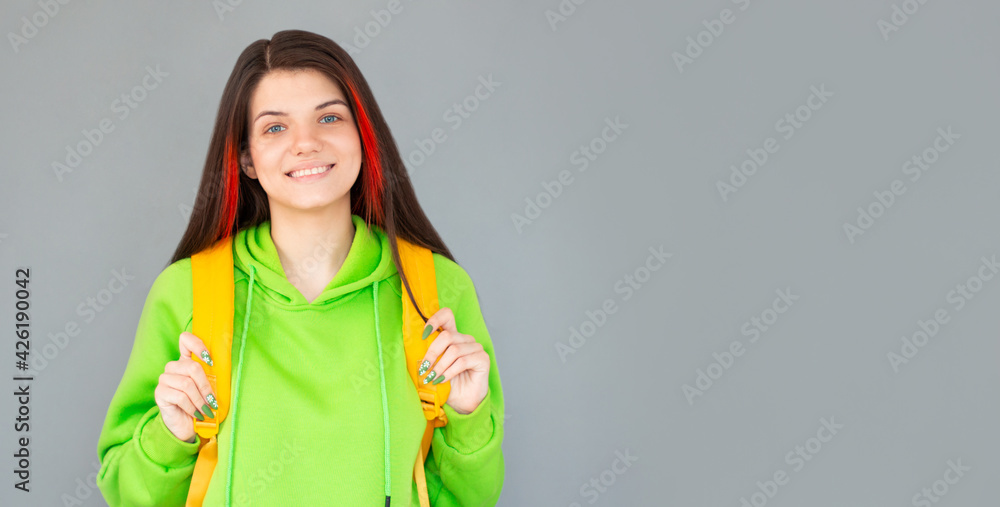 Indoor picture of young good-looking teenage girl isolated on gray background with yellow backpack Indoor picture of young good-looking teenage girl isolated on gray background with yellow backpack