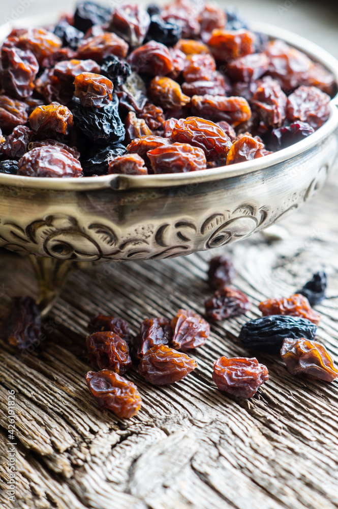 Dried grapes in silver bowl on wooden background, raisins Dried grapes in silver bowl on wooden background, raisins