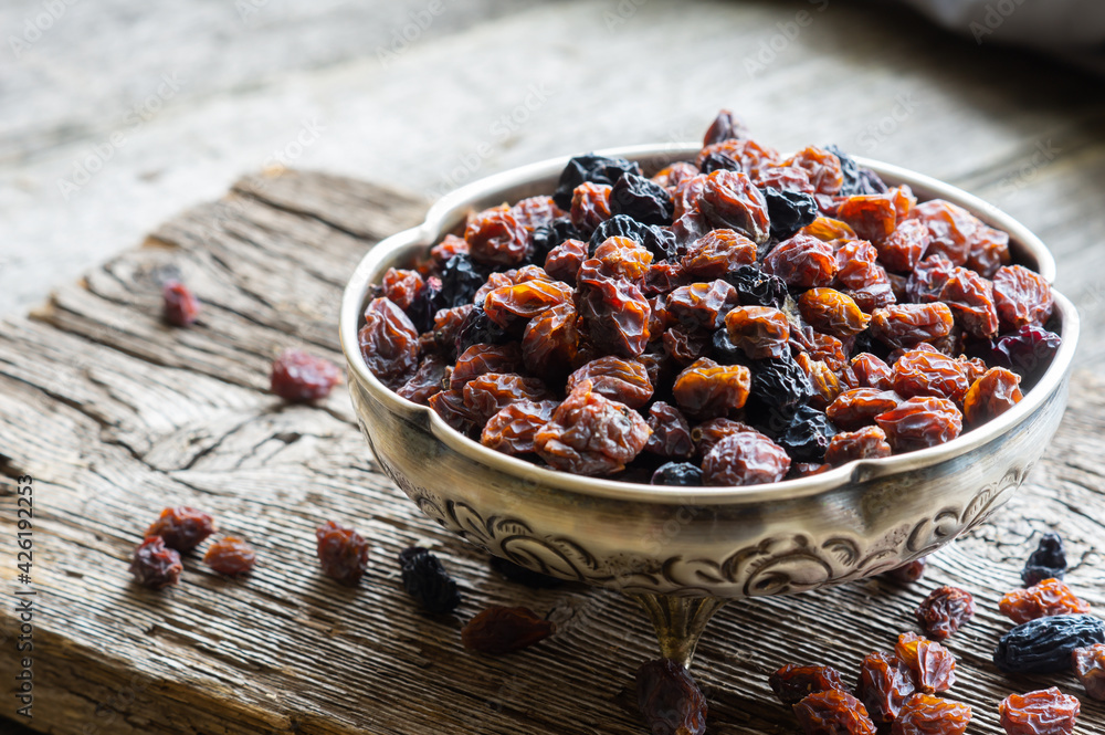 Dried grapes in silver bowl on wooden background, raisins Dried grapes in silver bowl on wooden background, raisins
