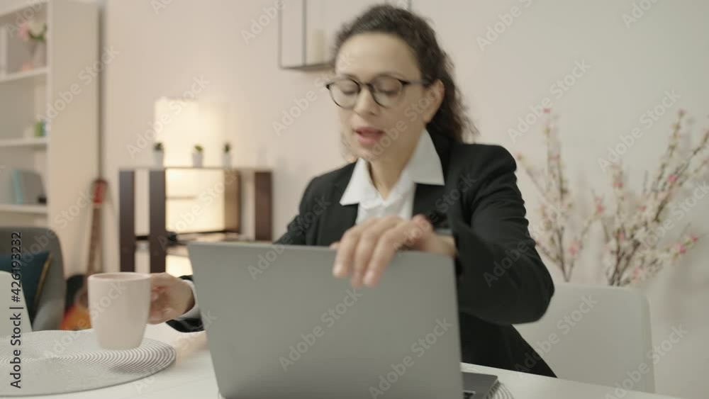 Busy young woman working on laptop, checking time, rushing to business meeting Busy young woman working on laptop, checking time, rushing to business meeting