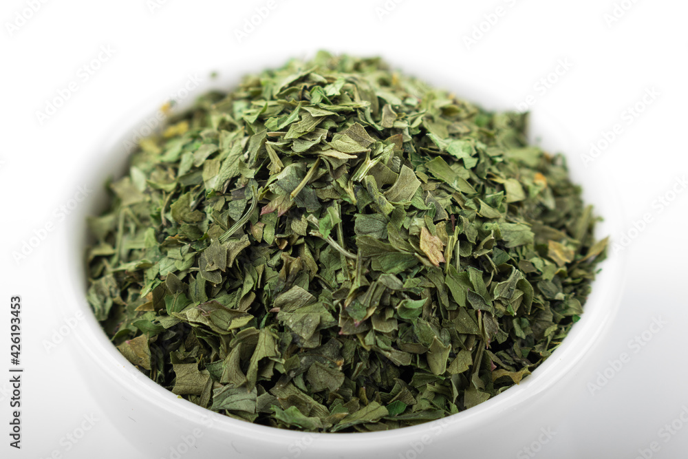 Dried parsley. Dried parsley in white bowl, on white background. Parsley. Dried parsley. Dried parsley in white bowl, on white background. Parsley.
