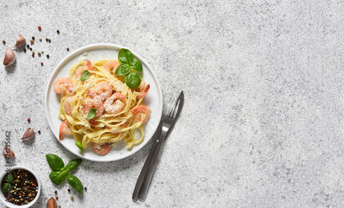 Tagliatelle pasta with creamy sauce, parmesan and shrimps in a plate on a concrete background. View from above.