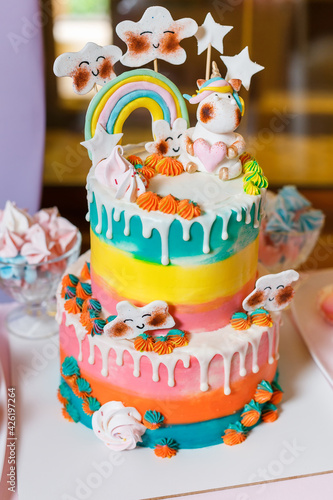 Big cake on the unicorn and rainbow theme. Sweets for children with fantasy style. Multi colored candy bar on birthday party with cupcakes and macaroons