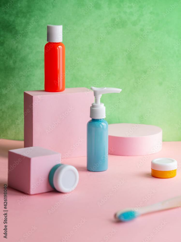 multicoloured bottles and jar with toothbrush on pink decoration and green background multicoloured bottles and jar with toothbrush on pink decoration and green background