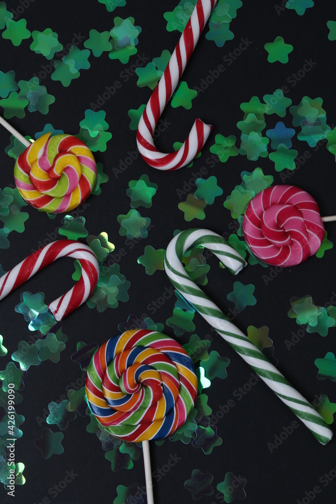 colored caramel on a stick lie on a black background with stars