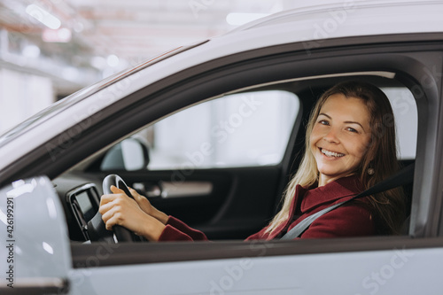 Portrait of a happy woman in her car, looking at camera.