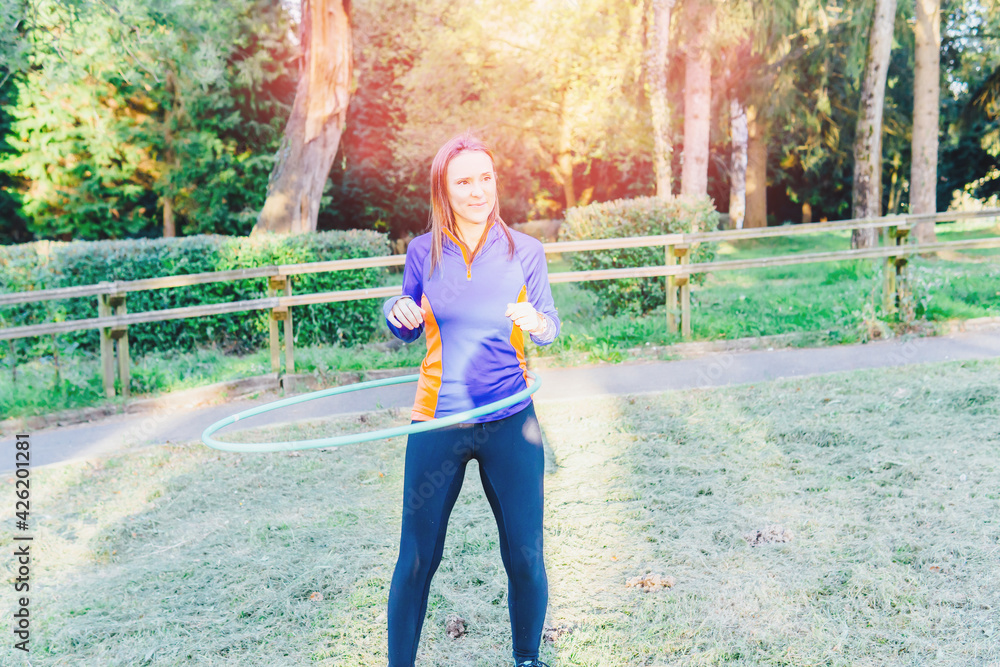 Beautiful athletic young adult woman training in a park hula hoop at sunset  point concept sport personal care outdoor sport foto de Stock | Adobe Stock