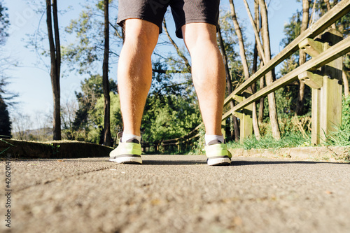 Rear view of legs and sneakers of a runner on the path of a park designed for running point concept personal care running