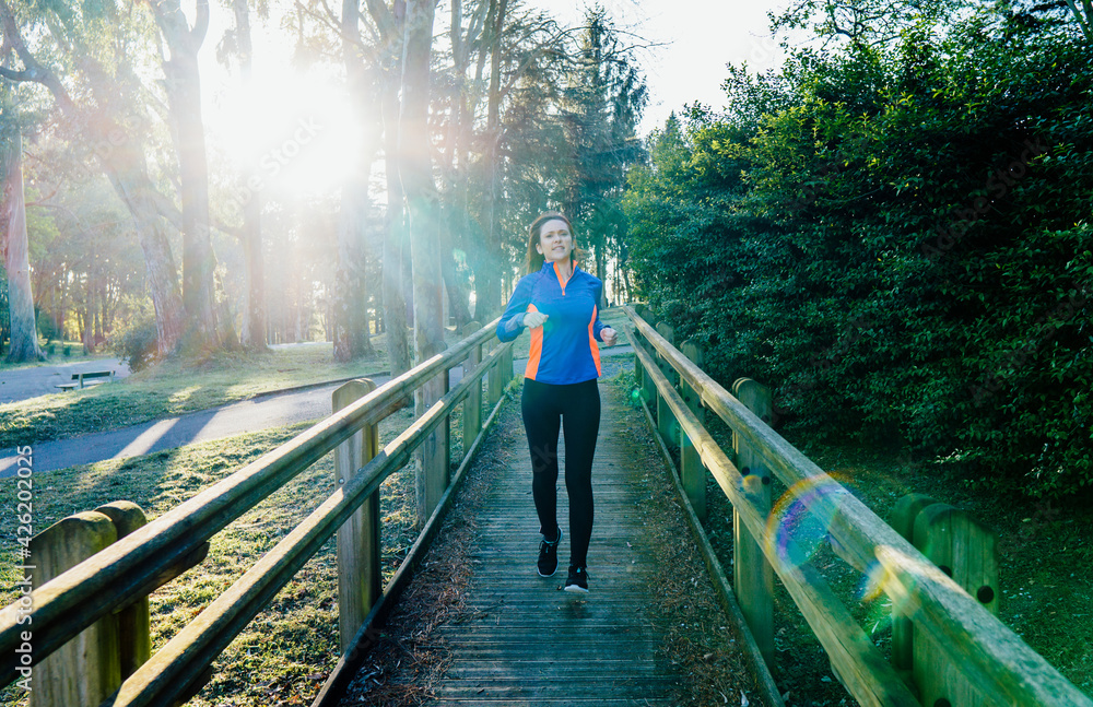 Fototapeta premium Young adult woman beautiful athlete training in a park at sunset in spring or summer point concept daily training elite training Personal care