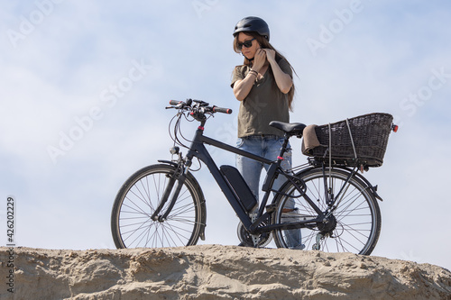 woman putting bicycle protective helmet and preparing for a ride