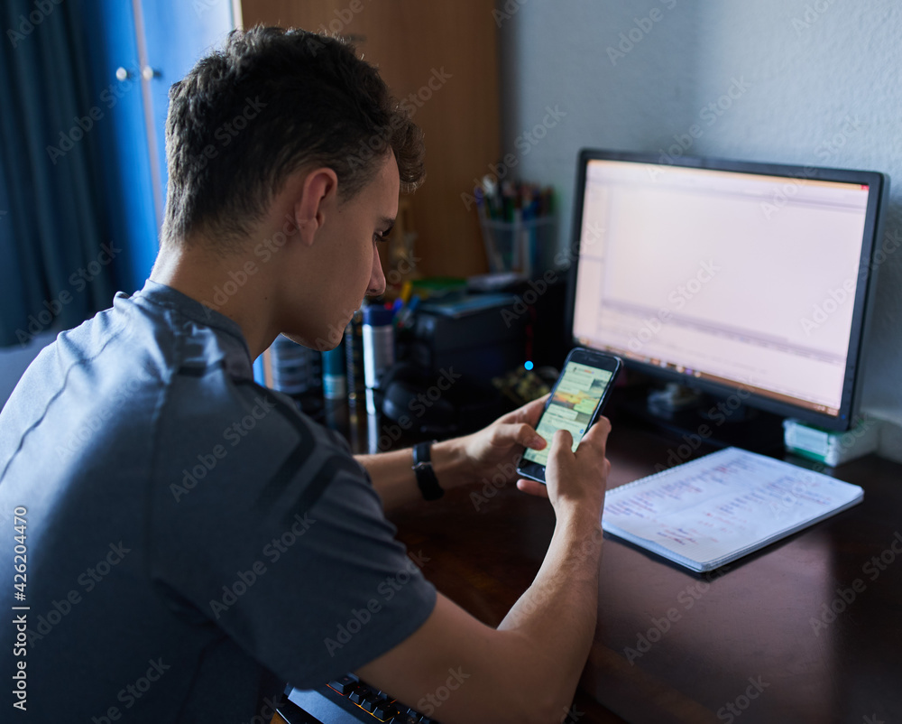 Student working with computer and cellphone Student working with computer and cellphone