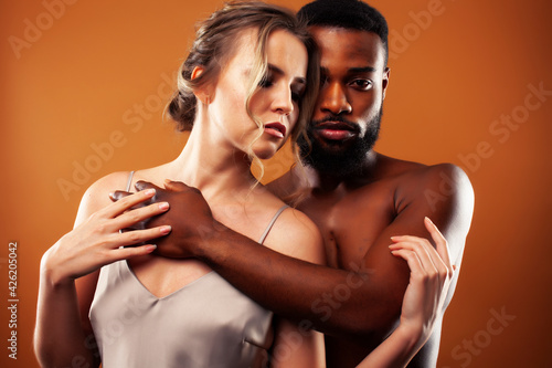 Young pretty couple diverse races together posing sensitive on brown background, lifestyle people concept