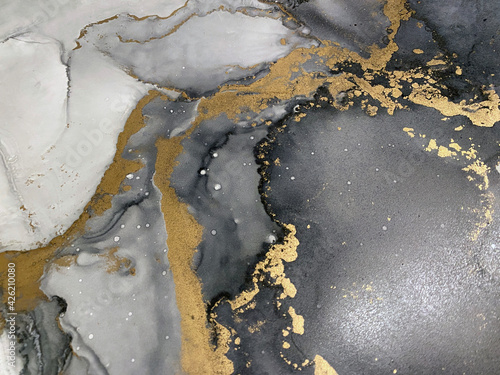 Abstract grey art with gold — black and white background with beautiful smudges and stains made with alcohol ink and golden pigment. Fluid art texture resembles watercolor or aquarelle. © Luvricon