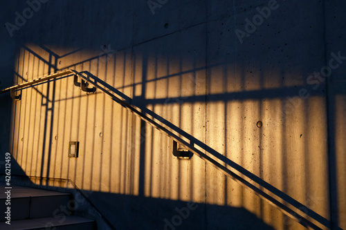 オレンジ色の夕日の光で照らされた外階段と手すり