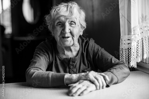 An old pensioner woman in her house. Black and white photo.