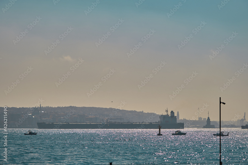 Turkey istanbul 04.03.2021. istanbul bosphorus during morning from with huge cargo transportation ships, small fishing boats in golden horn with sunshine reflection on the water and silhouette of city