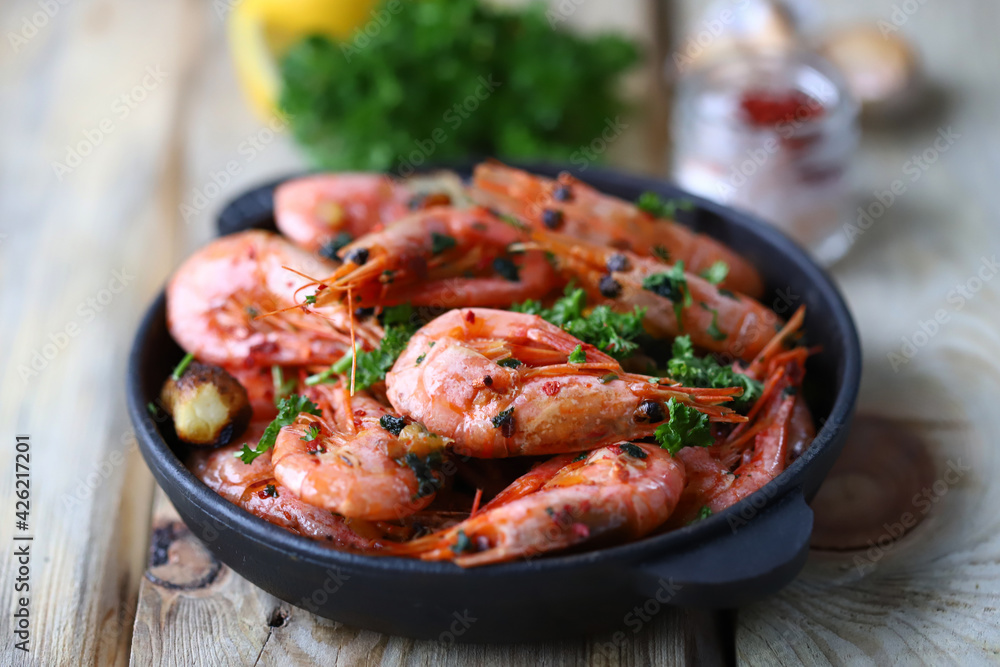 Shrimp in shells in a frying pan. Delicious fried prawns with spices.