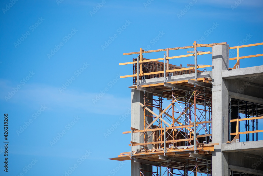 Upper floors of commercial concrete multi storey building with wooden scaffolding and guardrails during construction.