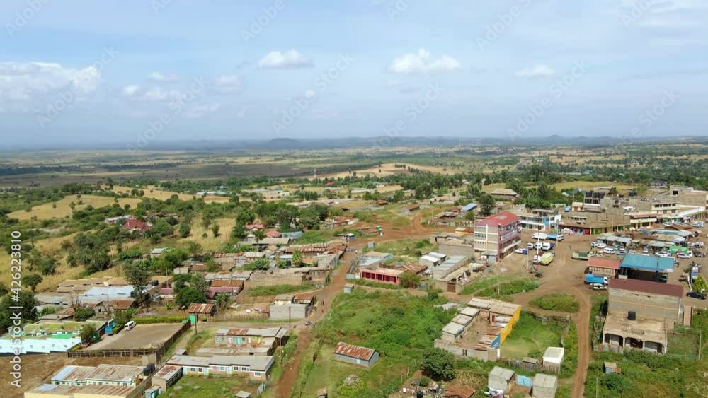 Aerial view overlooking a village and sunny Amboseli national park, in Kenya - rising, pan, drone shot Aerial view overlooking a village and sunny Amboseli national park, in Kenya - rising, pan, drone shot