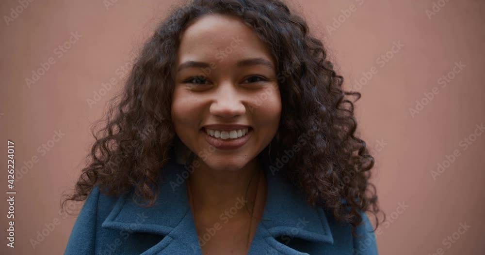 Close-up portrait of happy excited beautiful multiracial woman with curly hair smiling, posing at camera slow motion. Close-up portrait of happy excited beautiful multiracial woman with curly hair smiling, posing at camera slow motion.
