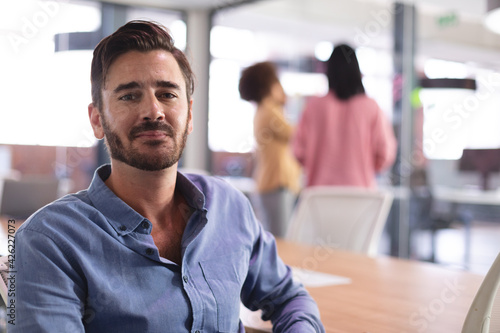 Portrait of happy caucasian businessman sitting at desk looking to camera photo