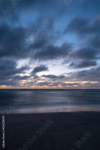 Dramatic long exposure of some clouds over the sea at the blue hour