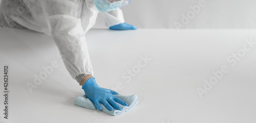 Closeup hand with glove  in virus protective suit and mask wipe cleaning covid19 infected area, Virus disinfection concept with copy space photo