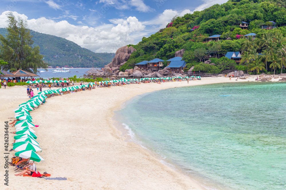 Row of beach umbrella parasols with wooden beach chairs on tropical sandy beach in sunny day at Koh Nang Yuan Island