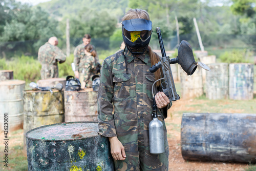 Portrait of upset woman in protective helmet with splash after direct hit in paintball game