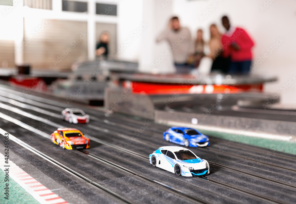 Fototapeta premium Toy remote control racing bright multicolored cars on the track and enthusiastic players