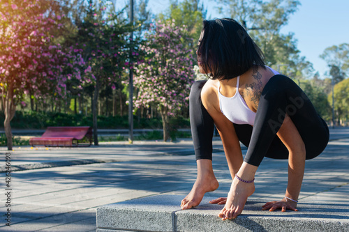 Beautiful young latina woman practicing yoga in the park. Yoga instructor