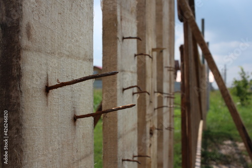 dangerous rusty nails stick out a point in a fence from boards spikes