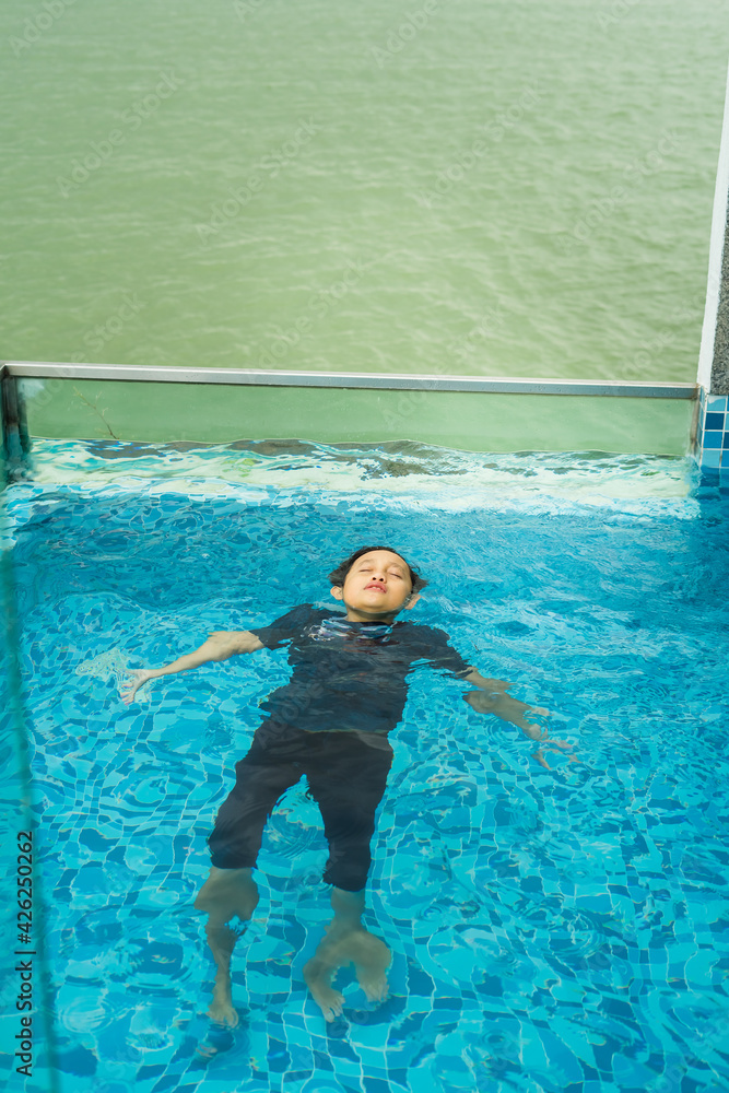 Young child in the pool. Kid having fun in swimming pool against the sea.