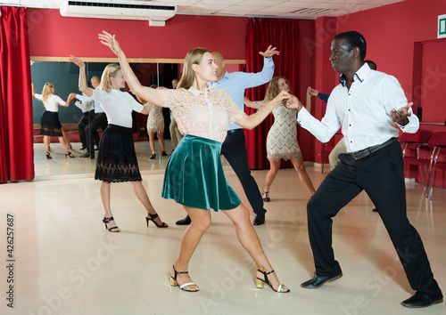 Portrait of young people dancing lindy hop in pairs in modern dance hall