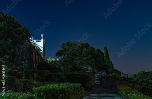 Landscape of night park on sea shore with clear sky with moon, dark tone. The walls and towers of the old palace on the background of a night sky