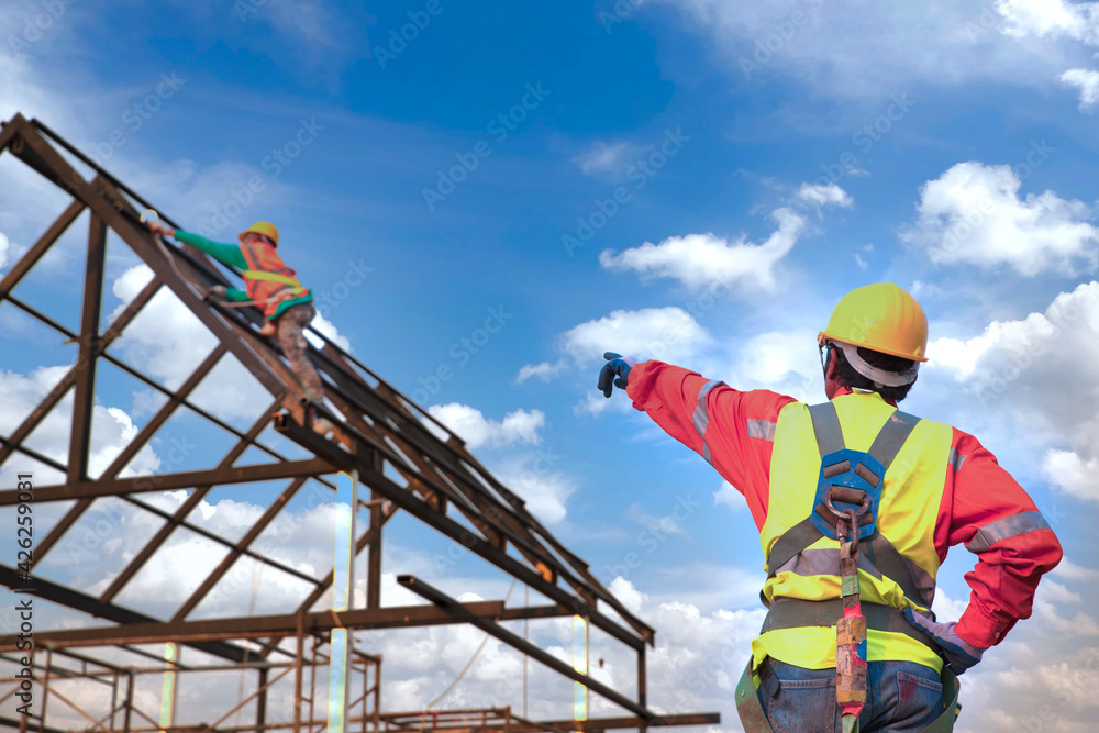 Engineer construction tecnician in a protective safety suit is pointing a team of workers on steel platform.Engineers are searching for and analyzing the unfinished construction project. Engineer construction tecnician in a protective safety suit is pointing a team of workers on steel platform.Engineers are searching for and analyzing the unfinished construction project.