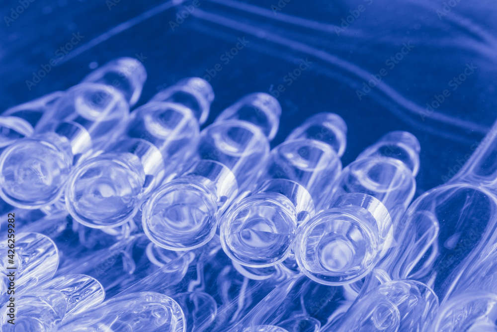 Glass medical ampoule vial for injection. Medicine is liquid sodium chloride with of aqueous solution in ampulla. Close up. Bottles ampule multicolor.