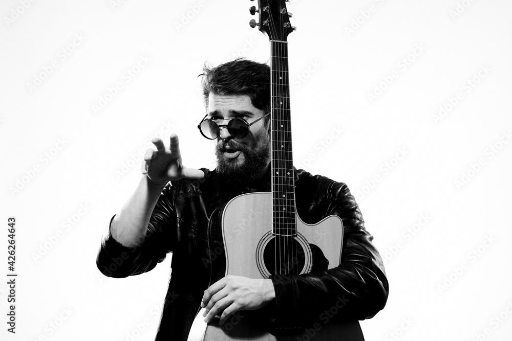 Obraz premium A man with a guitar black leather jacket light background performing a musician