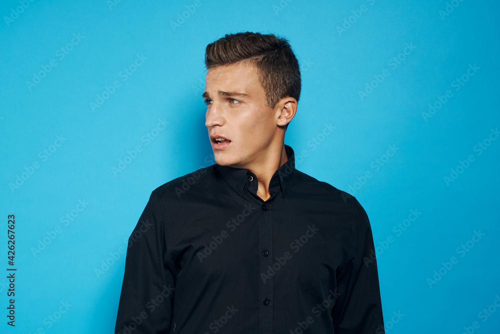 Obraz premium Cute man in black shirt emotions studio blue background