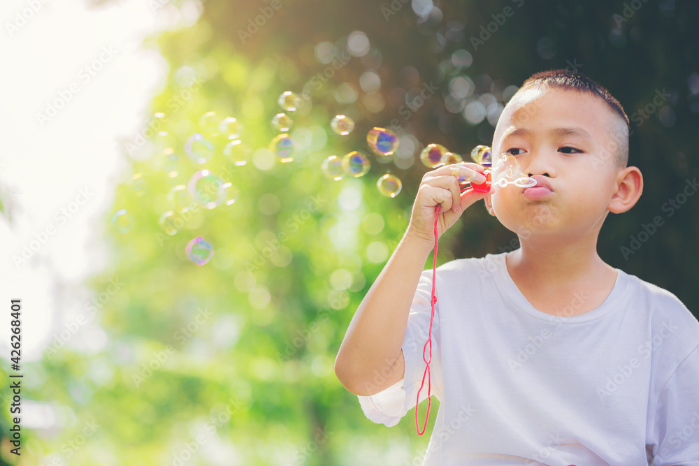 Asian little boy is blowing soap bubbles. Selected focus