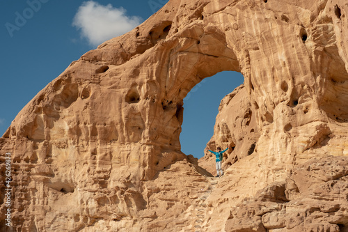 Female hiker posing at the Great Arch in Timna national park, southern Israel. Famous tourist attraction in the national park. Vacation in Israel. 