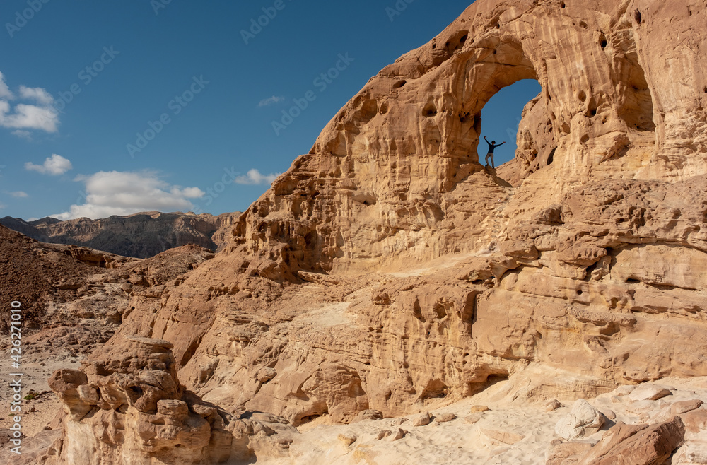 Female hiker posing at the Great Arch in the Timna national park, southern Israel. Famous tourist attraction in the national park. Vacation in Israel. 