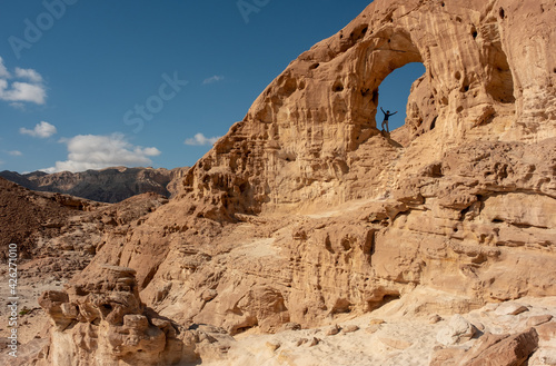 Female hiker posing at the Great Arch in the Timna national park  southern Israel. Famous tourist attraction in the national park. Vacation in Israel. 