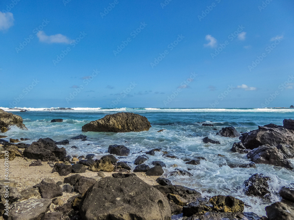Waves splashing over dark stones in Sengigi beach on the island of Lombok (next to Bali) in Indonesia.
