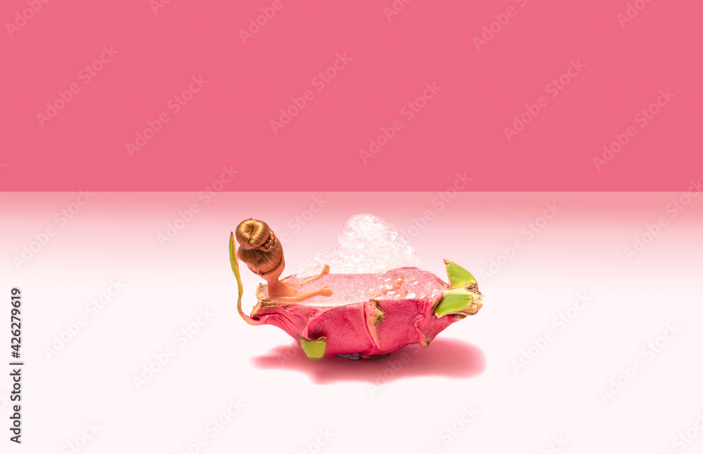 Minimal arrangement of fashion girl toy enjoying bubble bath with unique dragon fruit. Hot pink and pastel pink background. Minimal arrangement of fashion girl toy enjoying bubble bath with unique dragon fruit. Hot pink and pastel pink background.
